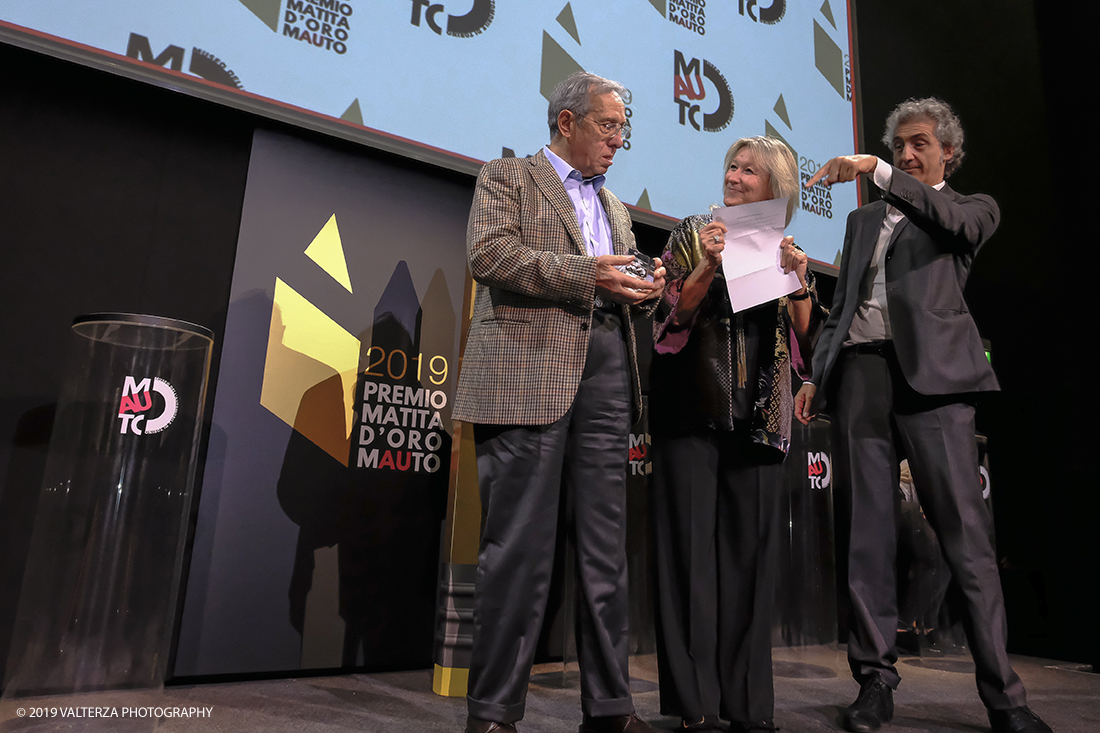 _DSF1548.jpg - 15/10/2019. Torino. Matita d'oro 2019. Anche quest'anno il Mauto ha assegnato i suoi prestigiosi premi al mondo dell'automobile. Nella foto Il premio MAUTO â€œCarlo Biscaretti di Ruffiaâ€� va allâ€™ Ing Mauro Forghieri  lâ€™insuperabile creativitÃ  ingegneristica e gli straordinari successi ottenuti su strada e su pista: durante gli anni in cui Ã¨ stato Direttore Tecnico della Scuderia Ferrari. Consegnano il premio  Mariella Mengozzi e Benedetto Camerana.