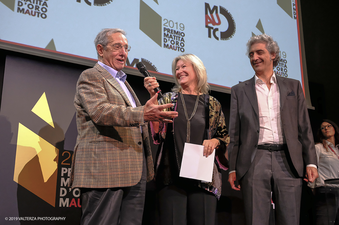 _DSF1565.jpg - 15/10/2019. Torino. Matita d'oro 2019. Anche quest'anno il Mauto ha assegnato i suoi prestigiosi premi al mondo dell'automobile. Nella foto Il premio MAUTO â€œCarlo Biscaretti di Ruffiaâ€� va allâ€™ Ing Mauro Forghieri  lâ€™insuperabile creativitÃ  ingegneristica e gli straordinari successi ottenuti su strada e su pista: durante gli anni in cui Ã¨ stato Direttore Tecnico della Scuderia Ferrari. Consegnano il premio  Mariella Mengozzi e Benedetto Camerana.