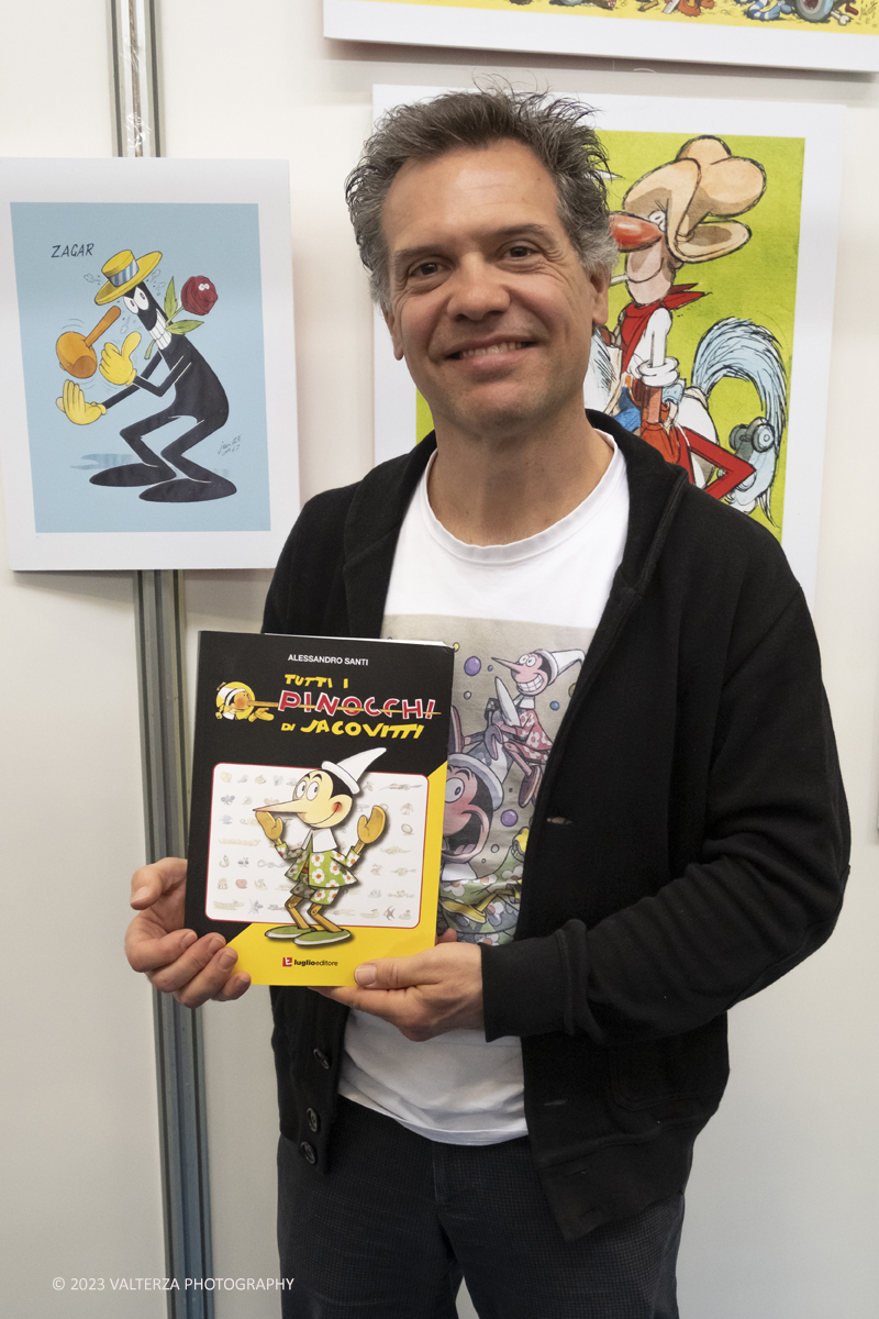 _DSF0405.jpg - 15/04/2023.Torino. Torino Comics celebra i 100 anni dalla nascita di Benito Jacovitti: 1923-2023 , uno degli autori italiani di fumetti piÃ¹ importanti del Novecento. Lâ€™autore Alessandro Santi, Dino Aloi  Marco Di Nicola e salvagno Luca hanno presentato il nuovo libro Tutti i Pinocchi di Jacovitti (Luglio ed.) allo stand di Poste Italiane Ã¨ stata  allestita una mostra dedicata a Jacovitti ed erano disponibili prodotti dedicati allâ€™artista, tra cui una litografia che ritrae il personaggio di Coccobill, un folder e un cofanetto con sei cartoline. Nella foto Alessandro Santi autore del libro Tutti i Pinocchi di Jacovitti