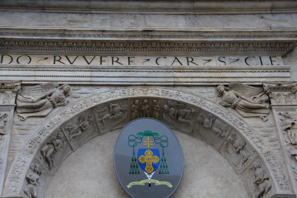 Nuvole_024.JPG - Torino - Duomo - Sculture della volta del portone principale di ingresso con stemma arcivescovile. In alto due Angeli e nell'arcata figure di musici. La scritta in alto: DO ° RUVERE ° CAR ° S.CLE (Domenico Della Rovere cardinale di San Clemente) fu incisa per perpetuare nel marmo il ricordo del committente dell'opera la cui prima pietra fu posata il 22 Luglio 1491.